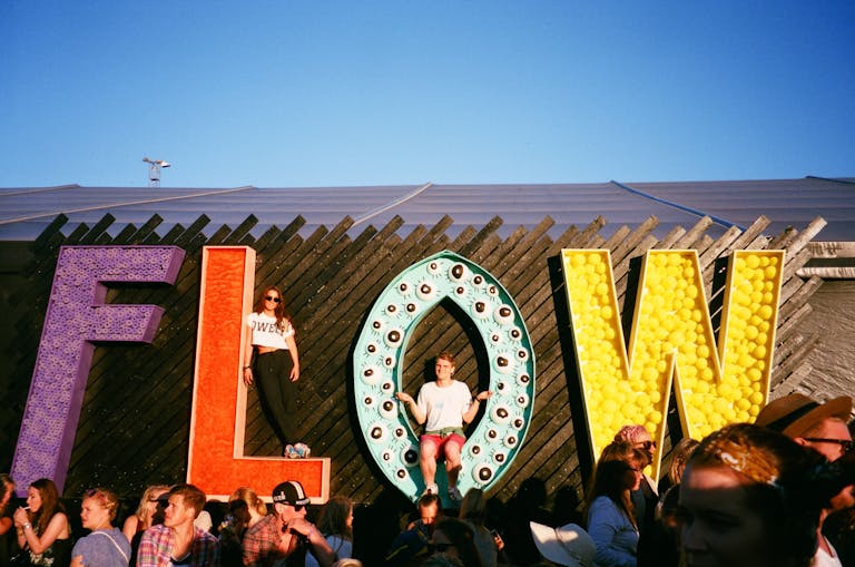 Group of People Gathering Near Frees Standing Flow Letters