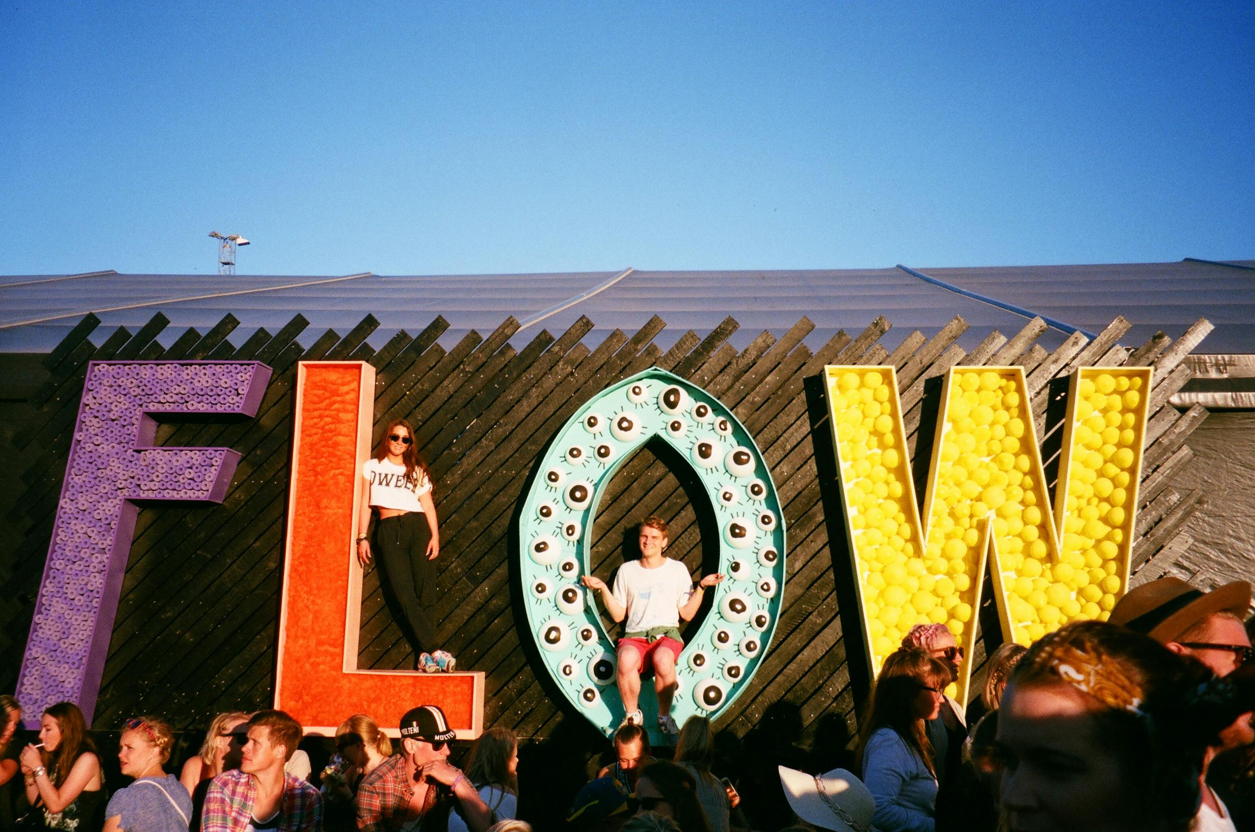 Group of People Gathering Near Frees Standing Flow Letters