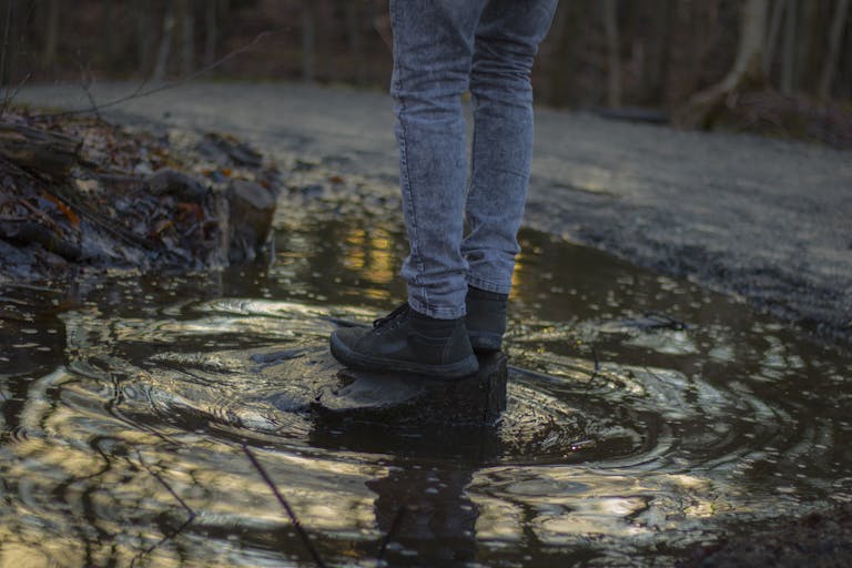 Man Jumping on Water Surrounded by Trees