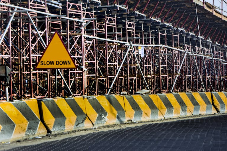 Construction site with a 'Slow Down' sign amid scaffolding in Kuwait.