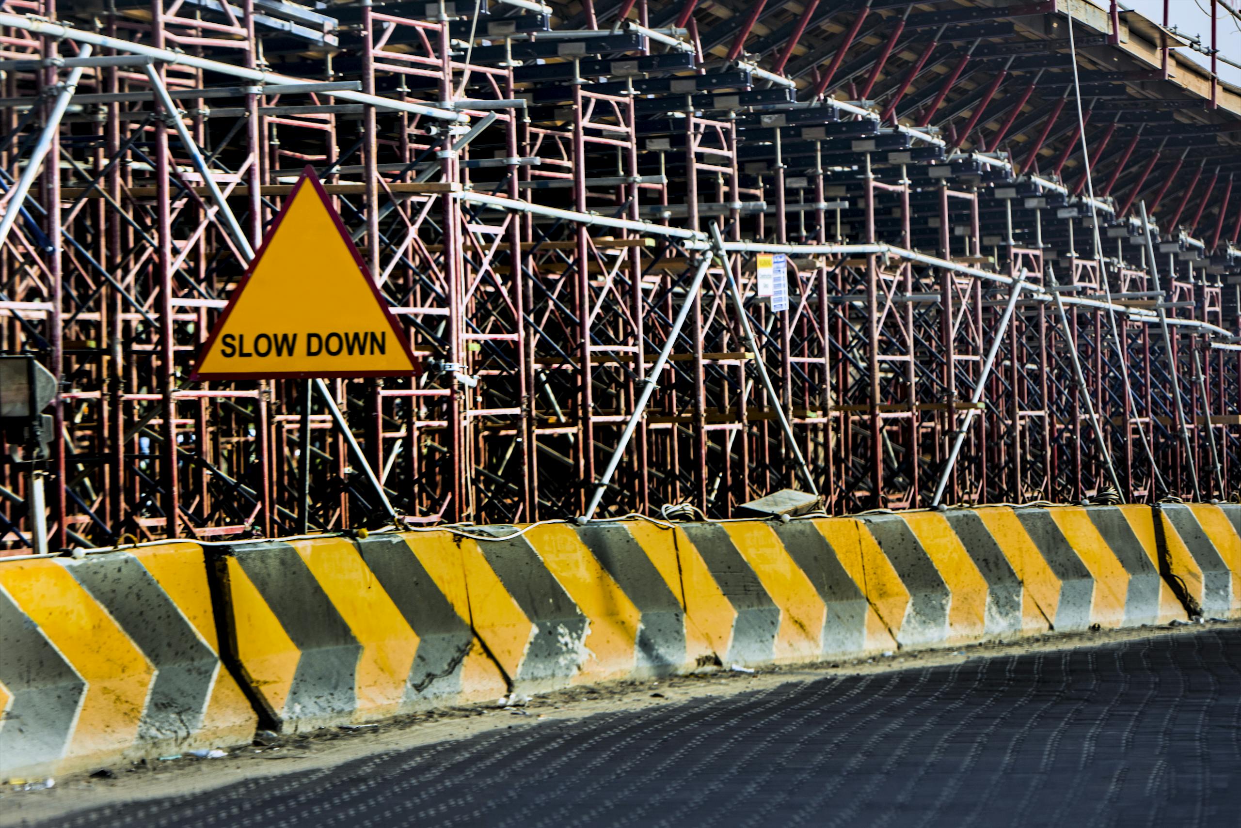 Construction site with a 'Slow Down' sign amid scaffolding in Kuwait.