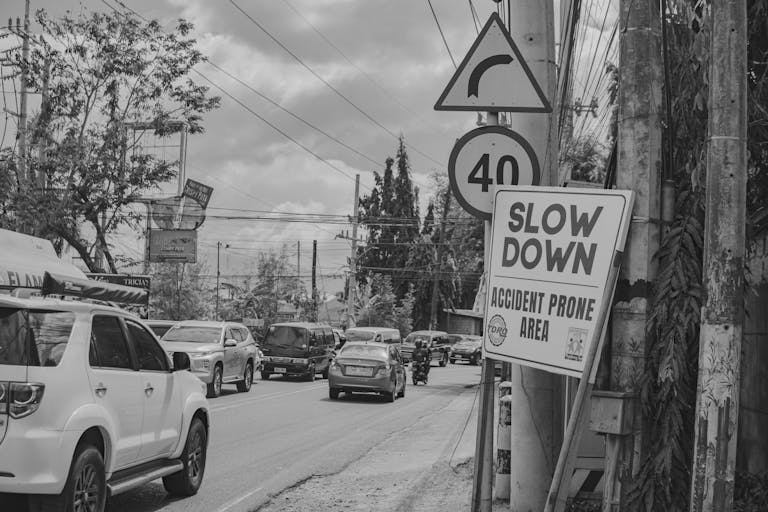 Black and white photo of a busy urban street with vehicles and road signs.